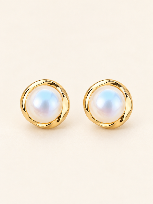 Pearl Glow gold-tone pearl stud earrings on a soft ivory cream background.