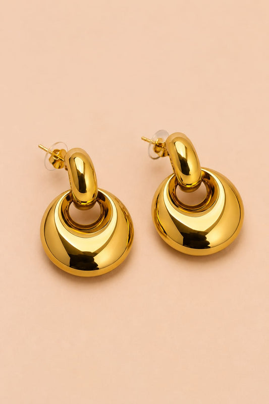 Three-quarter view of Valoria London Aurelia polished gold statement earrings with sculptural drop design