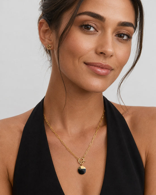 Noir Signet black and gold pendant necklace with paperclip chain displayed on a soft neutral background