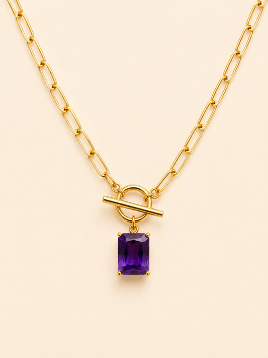 Purple Radiance 18K gold-plated toggle necklace with rectangular purple gemstone pendant on a soft ivory cream background.