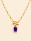 Purple Radiance 18K gold-plated toggle necklace with rectangular purple gemstone pendant on a soft ivory cream background.
