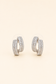 Silver crossover hoop earrings featuring baguette-cut and pavé crystals on a soft ivory cream background.