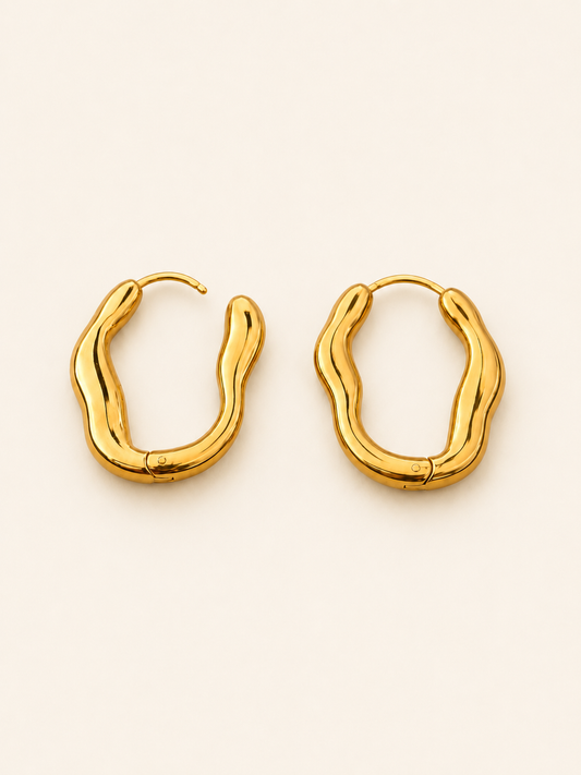 A pair of gold-toned, wavy open hoop earrings on a clean, solid off-white background.