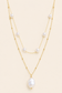 Aurelia baroque pearl layered gold necklace with two chains and white pearl accents on soft ivory cream background