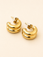 A pair of gold crescent-shaped hoop earrings with a polished finish and clear plastic backing, displayed on a light beige background.