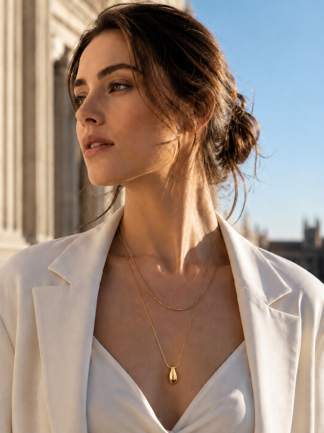 Woman wearing Elara gold teardrop layered necklace with elegant cream outfit