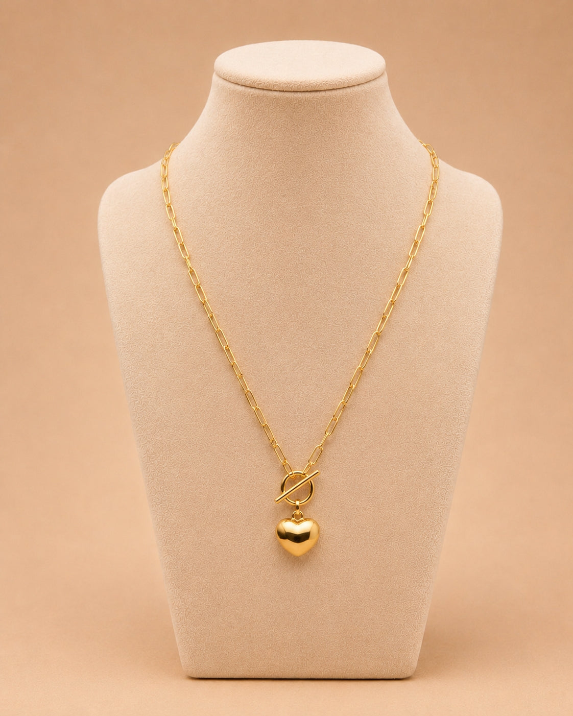 Gold heart pendant toggle necklace displayed on a cream jewellery bust