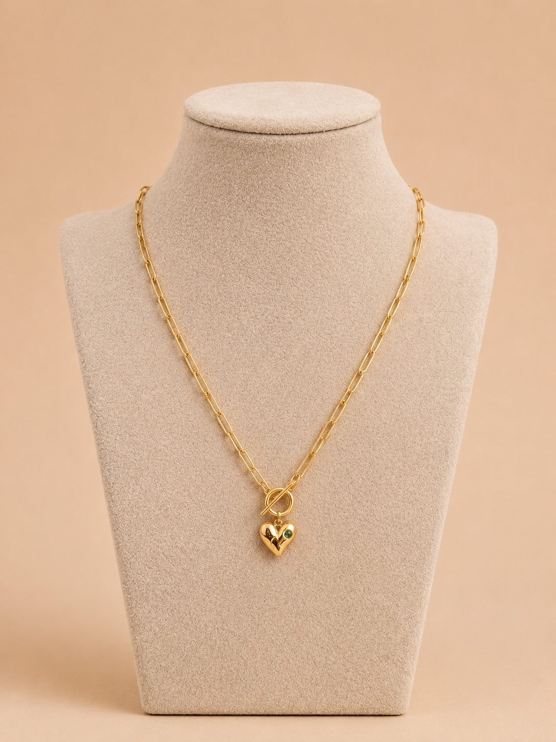 Gold heart pendant toggle necklace displayed on a cream jewellery bust