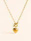 A gold paperclip chain necklace with a toggle clasp and a dangling heart-shaped charm, shown on a light cream background.