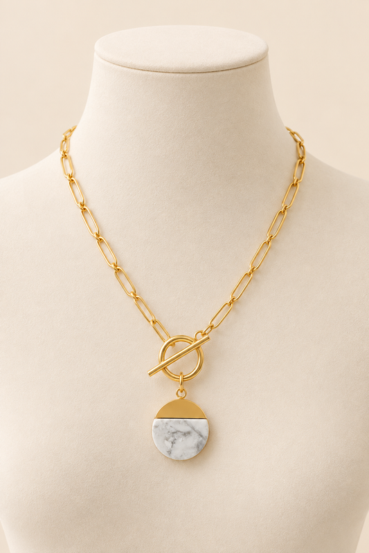 Ivory Aurelia gold toggle necklace with white marble-effect pendant on cream mannequin