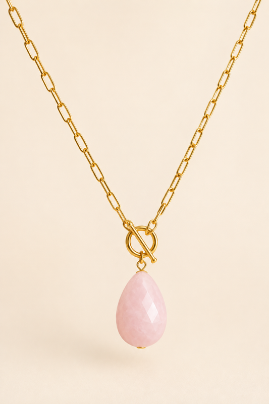 Close-up of gold toggle necklace with pink teardrop pendant