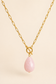 Close-up of gold toggle necklace with pink teardrop pendant