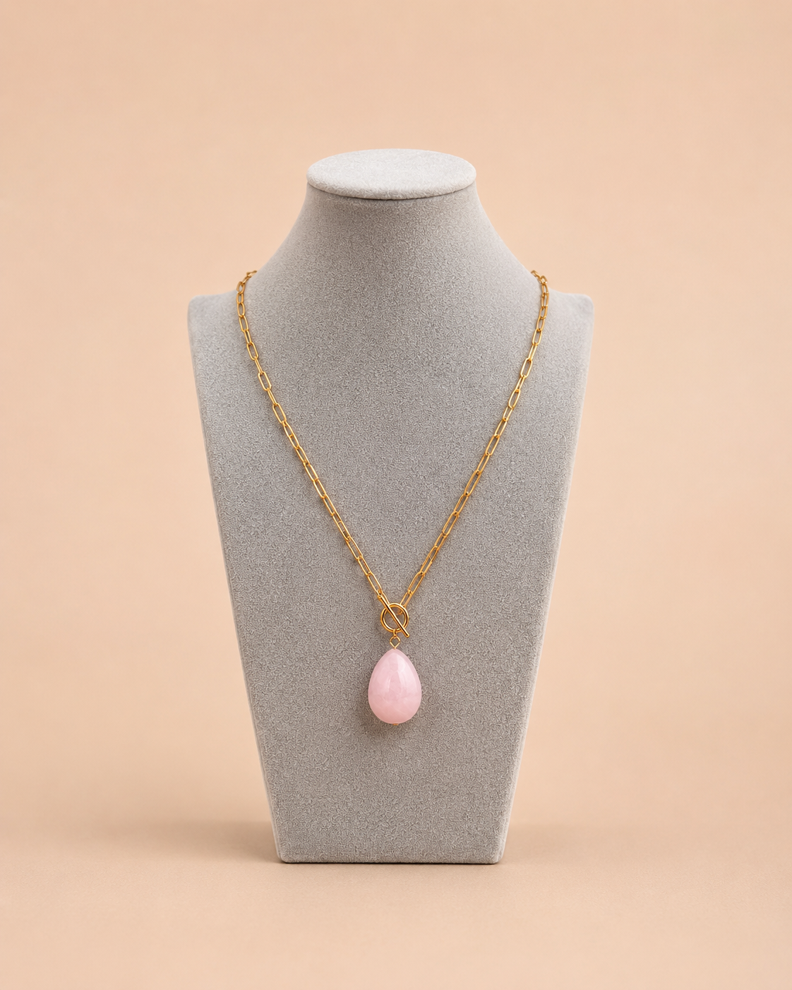 Gold toggle necklace with pink teardrop pendant displayed on mannequin