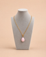 Gold toggle necklace with pink teardrop pendant displayed on mannequin