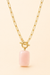 A gold paperclip chain necklace with a toggle clasp and a smooth, rectangular pale pink stone pendant, shown against a solid light beige background.