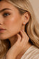 Model wearing round solitaire crystal stud earrings in a close-up jewellery look.