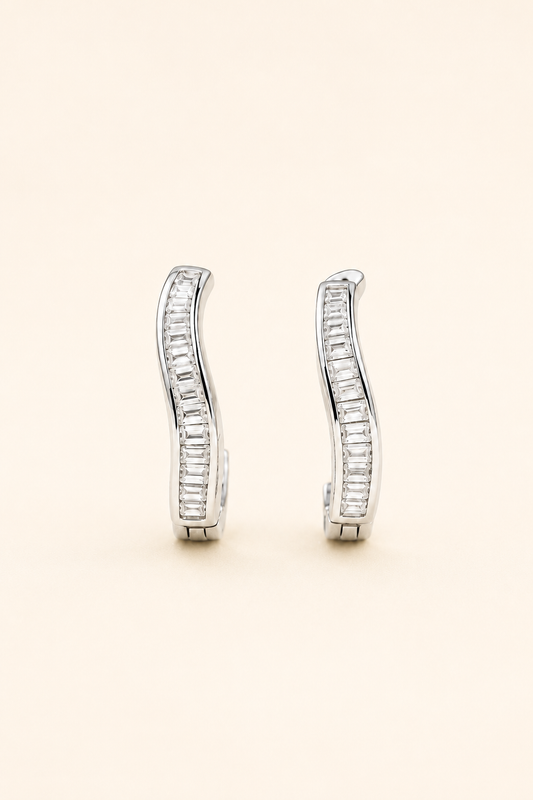 Silver baguette crystal huggie earrings on a soft ivory cream background.