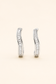 Silver baguette crystal huggie earrings on a soft ivory cream background.