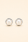 A pair of round stud earrings featuring white faux pearls set in polished silver-tone metal, displayed on a solid light beige background.