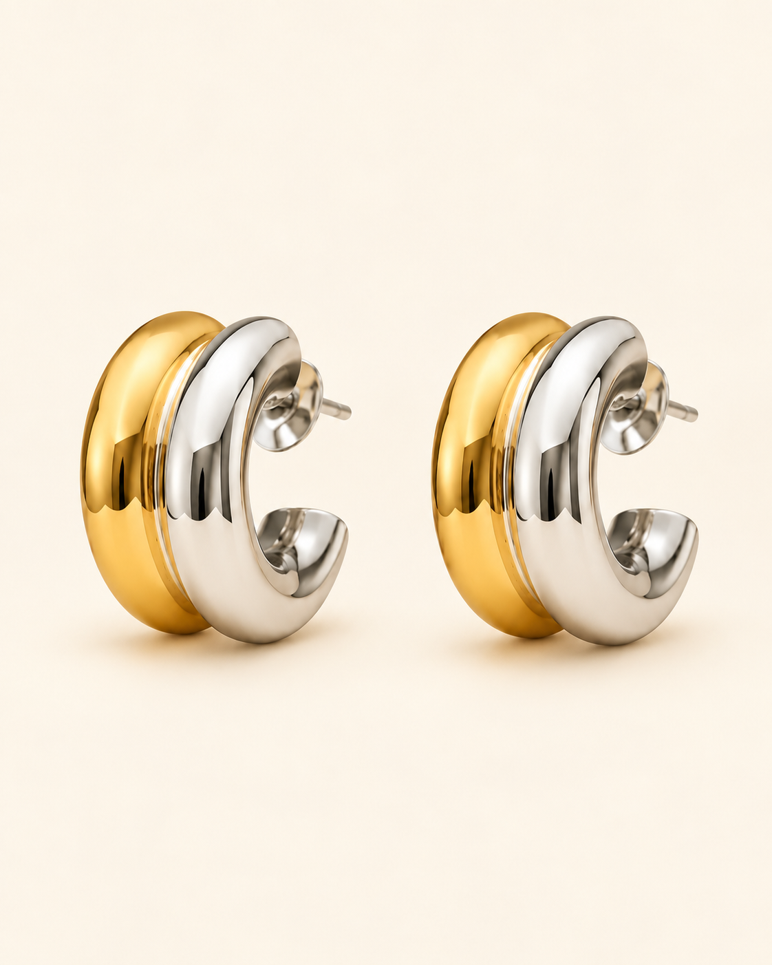 Two-tone gold and silver sculpted hoop earrings on soft ivory cream background