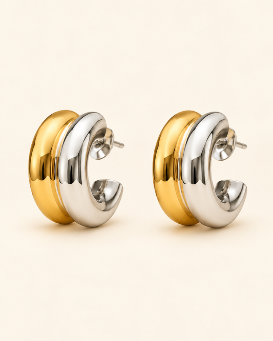 Two-tone gold and silver sculpted hoop earrings on soft ivory cream background