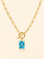 Gold paperclip chain necklace with a toggle clasp and a rectangular light blue gemstone pendant, shown on a light cream background.