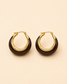 A pair of gold hoop earrings with a dark brown crescent-shaped inlay, displayed on a solid light beige background.