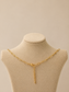 Gold paperclip necklace with lobster clasp and extender chain on a nude background