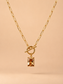 Close-up of gold toggle necklace with rectangular amber crystal pendant on a nude background