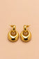 Pair of Valoria London Aurelia gold statement drop earrings displayed against a soft peach background