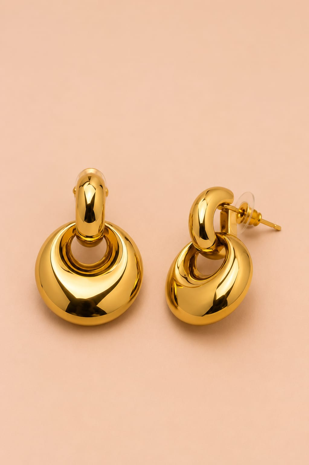 Angled view of Valoria London Aurelia gold drop earrings showing the curved upper link and rounded statement drop