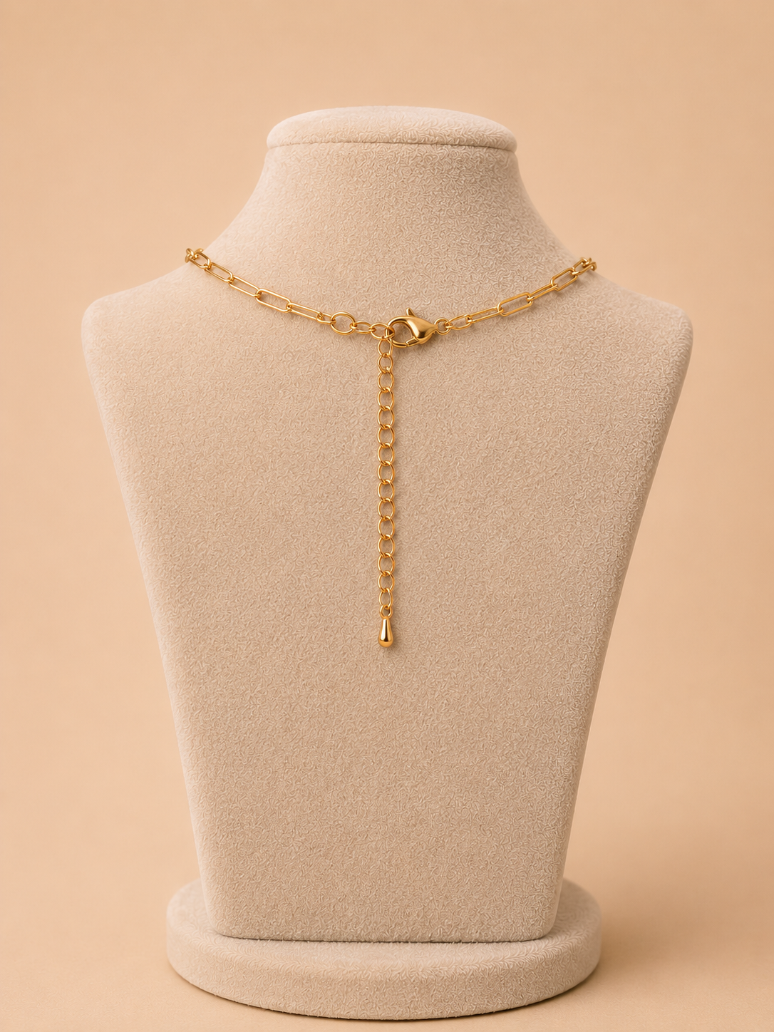 Back view of a gold paperclip necklace with lobster clasp and extender chain on a cream jewellery mannequin