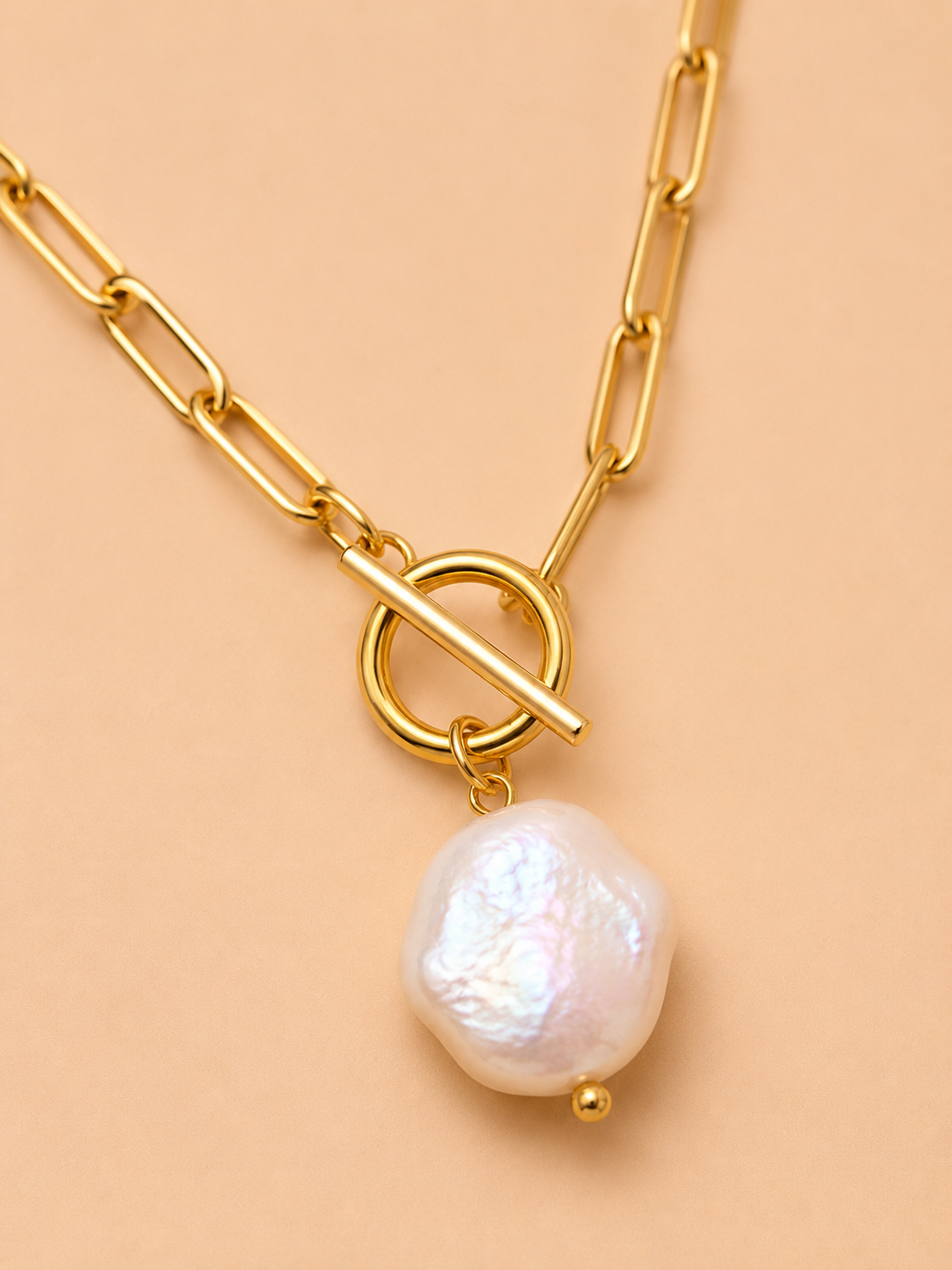 Close-up of the Valoria London Elara gold paperclip chain necklace with toggle detail and irregular pearl-effect pendant