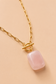 Close-up of Valoria London gold toggle necklace featuring a polished rectangular pink stone pendant
