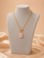 Valoria London gold paperclip chain toggle necklace with pink rectangular pendant displayed on soft satin
