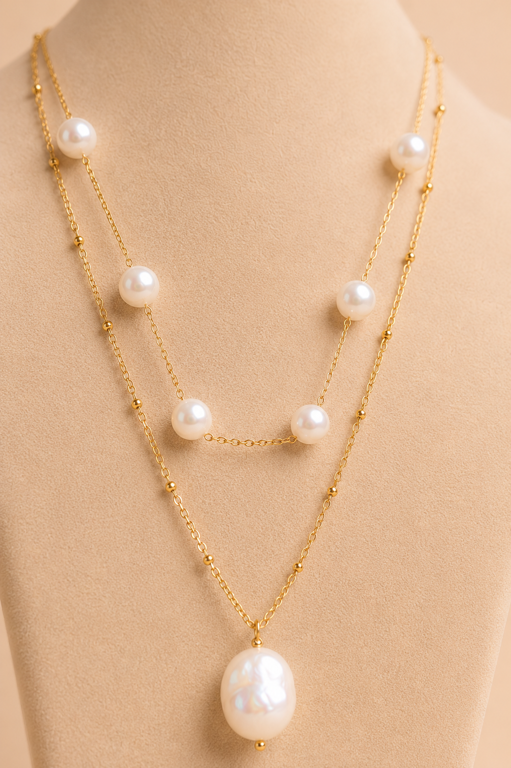 Close-up of layered gold necklace with white pearl details and a large pearl pendant