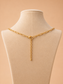 Back view of a gold paperclip necklace with lobster clasp and extender chain on a cream jewellery mannequin