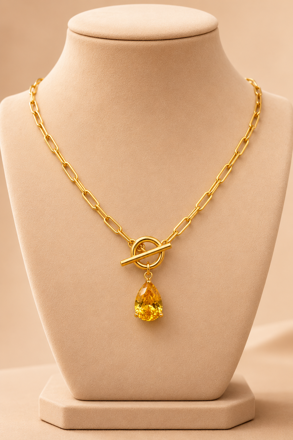 Valoria London gold paperclip necklace with yellow teardrop crystal pendant on a cream jewellery mannequin